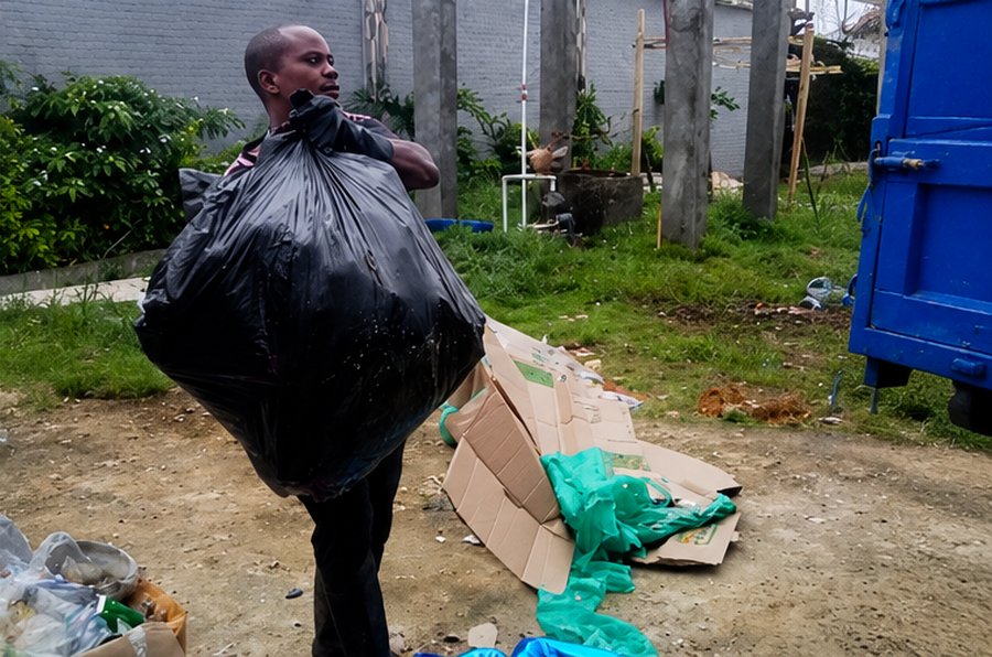 Israel Sanitation Solutions crew member carrying a full waste bag to the truck