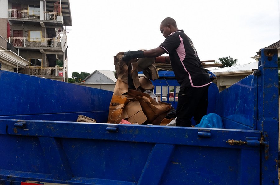 Israel Sanitation Solutions crew member loading cardboard and recyclables into the collection truck